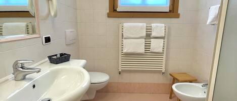 Un baño moderno con lavamanos, inodoro, bidé y ventana.