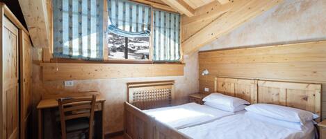 Una habitación de madera con una cama, un escritorio y una silla.