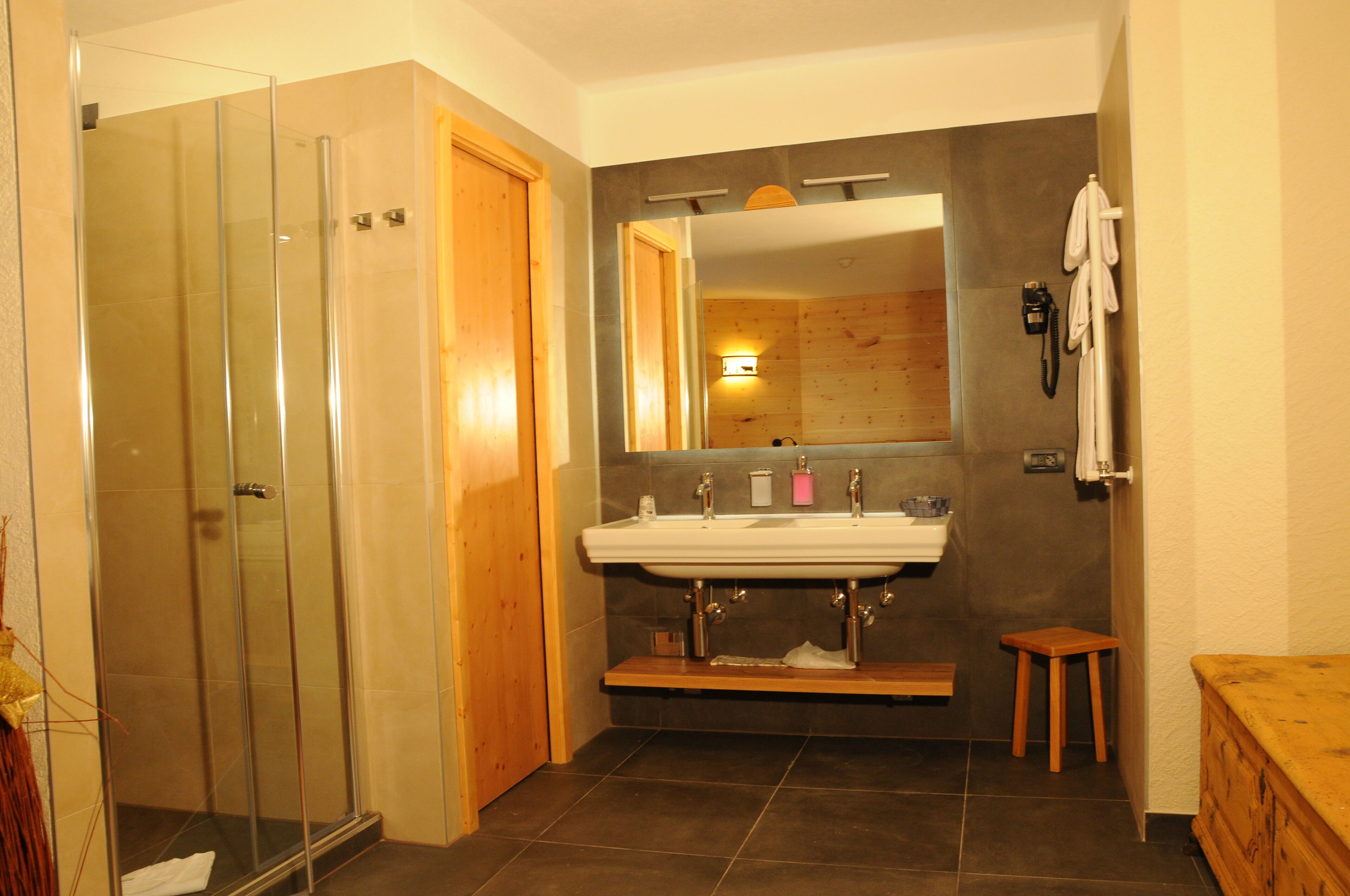 A bathroom with a glass shower enclosure, a wooden vanity, and a large mirror.