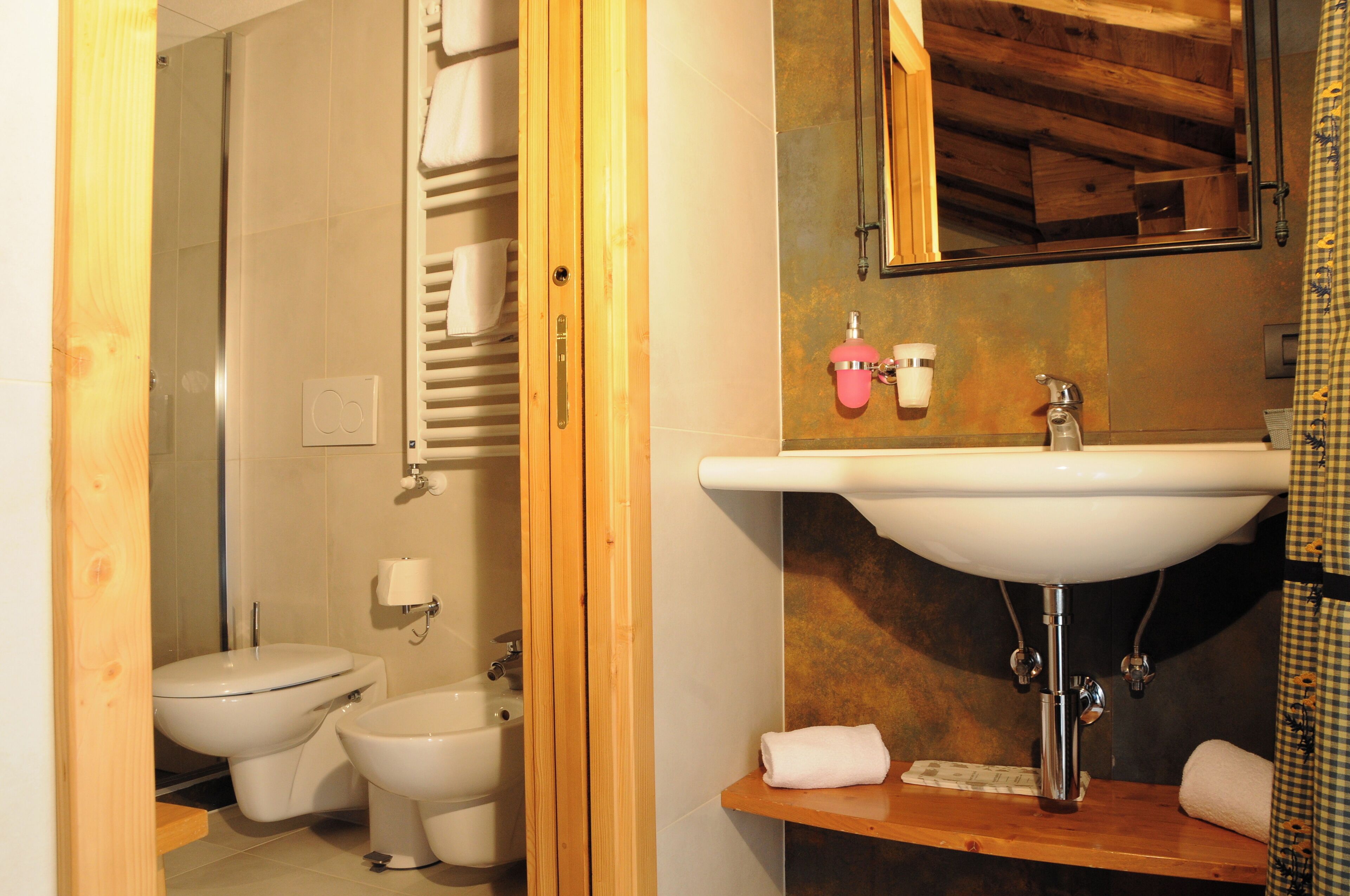 A bathroom with a sink, mirror, and two toilets.