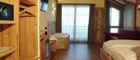 Un dormitorio con piso de madera, una cama, una mesita con una botella y un televisor montado en la pared.