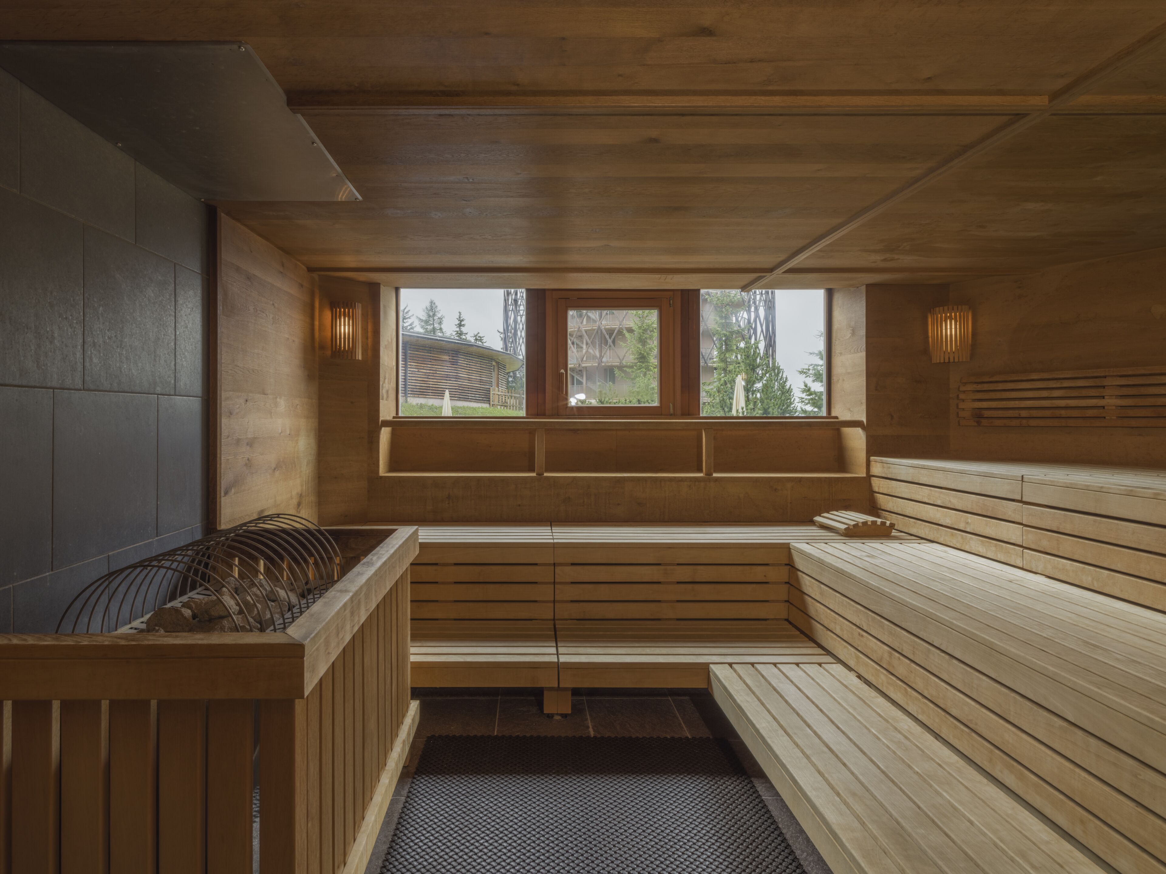 Un sauna avec des bancs en bois et une fenêtre donnant sur l’extérieur.