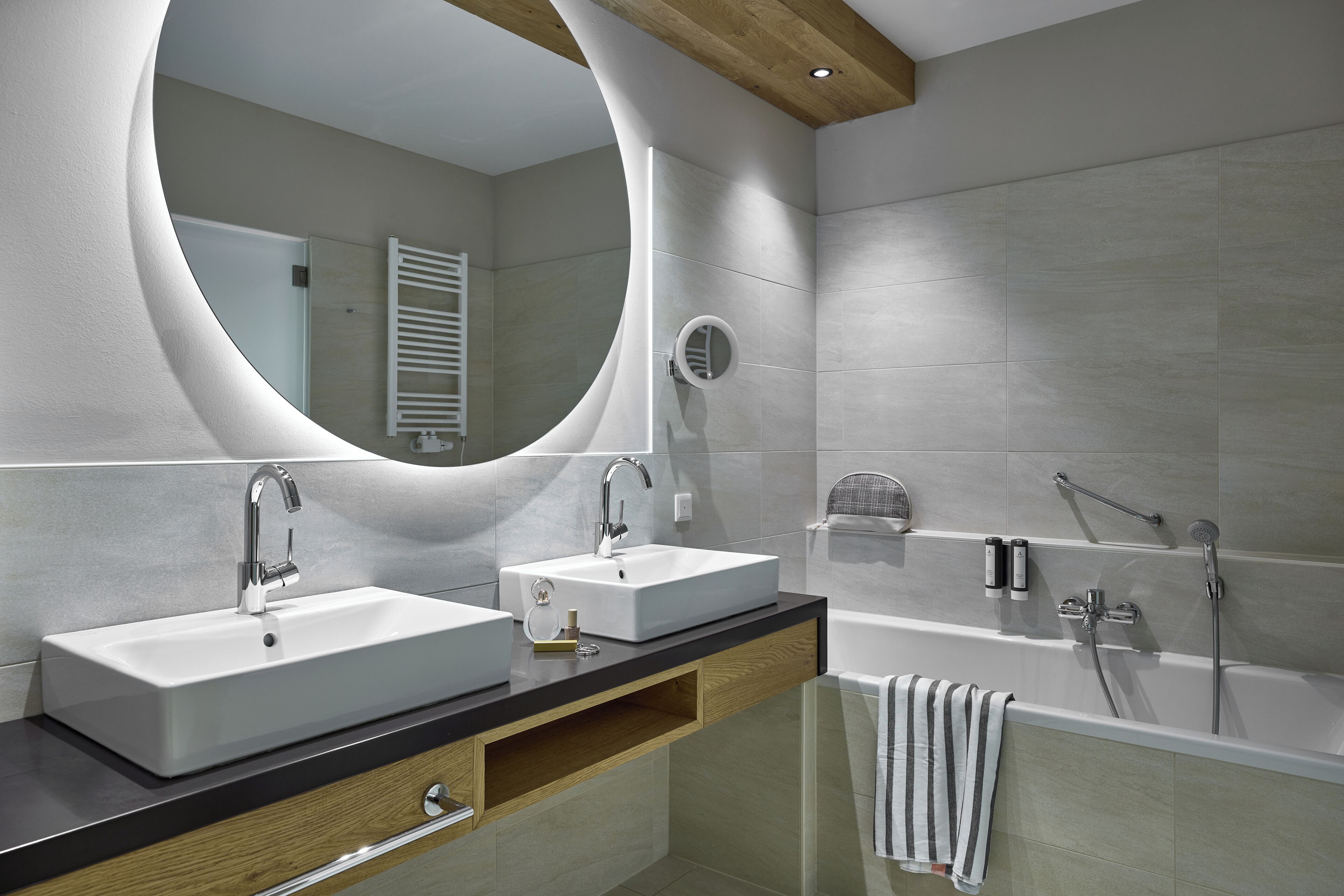 Un baño moderno con dos lavamanos, un espejo grande, una bañera y un perchero para toallas.