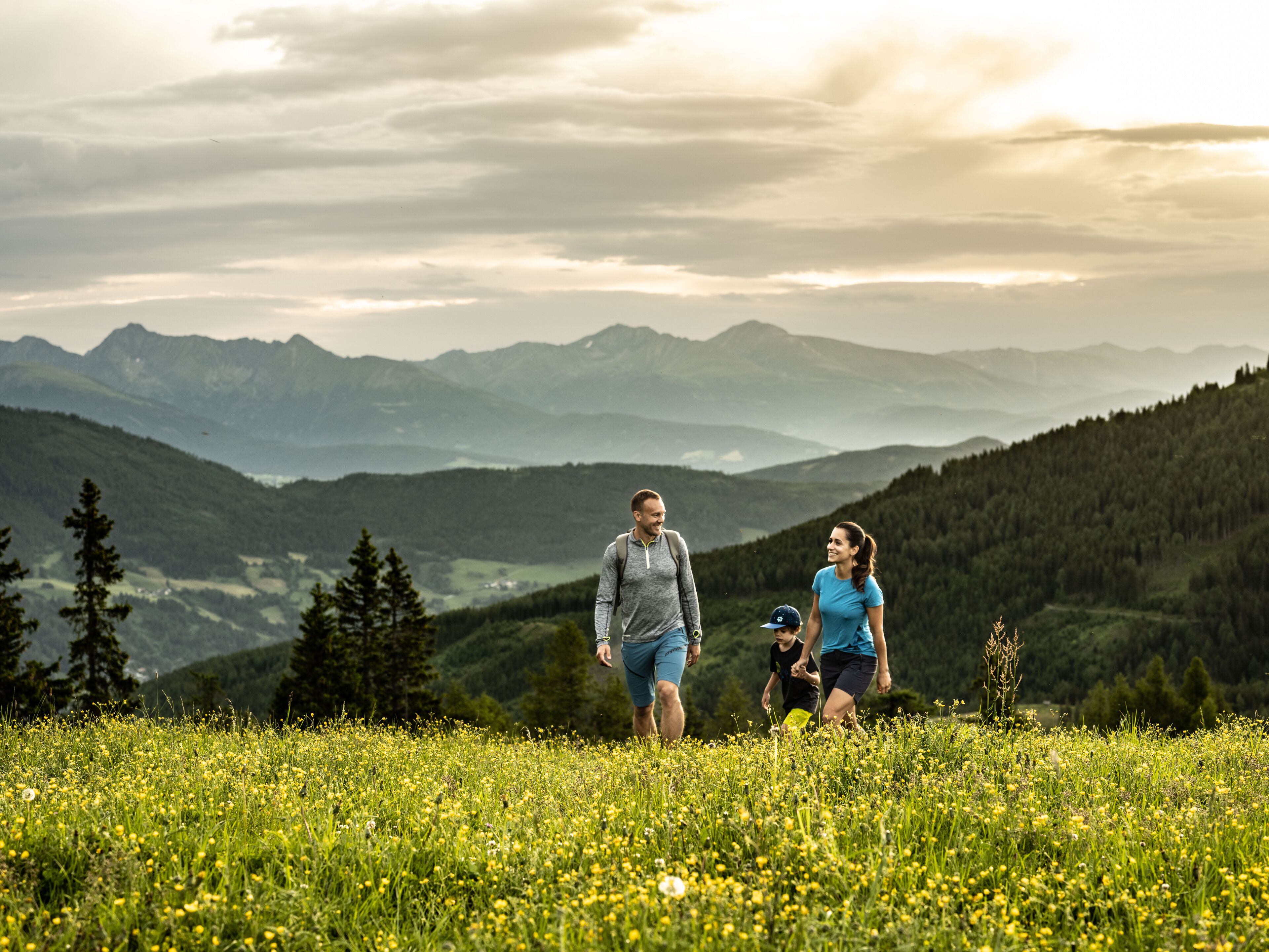 A family walking in a field with mountains in the background.