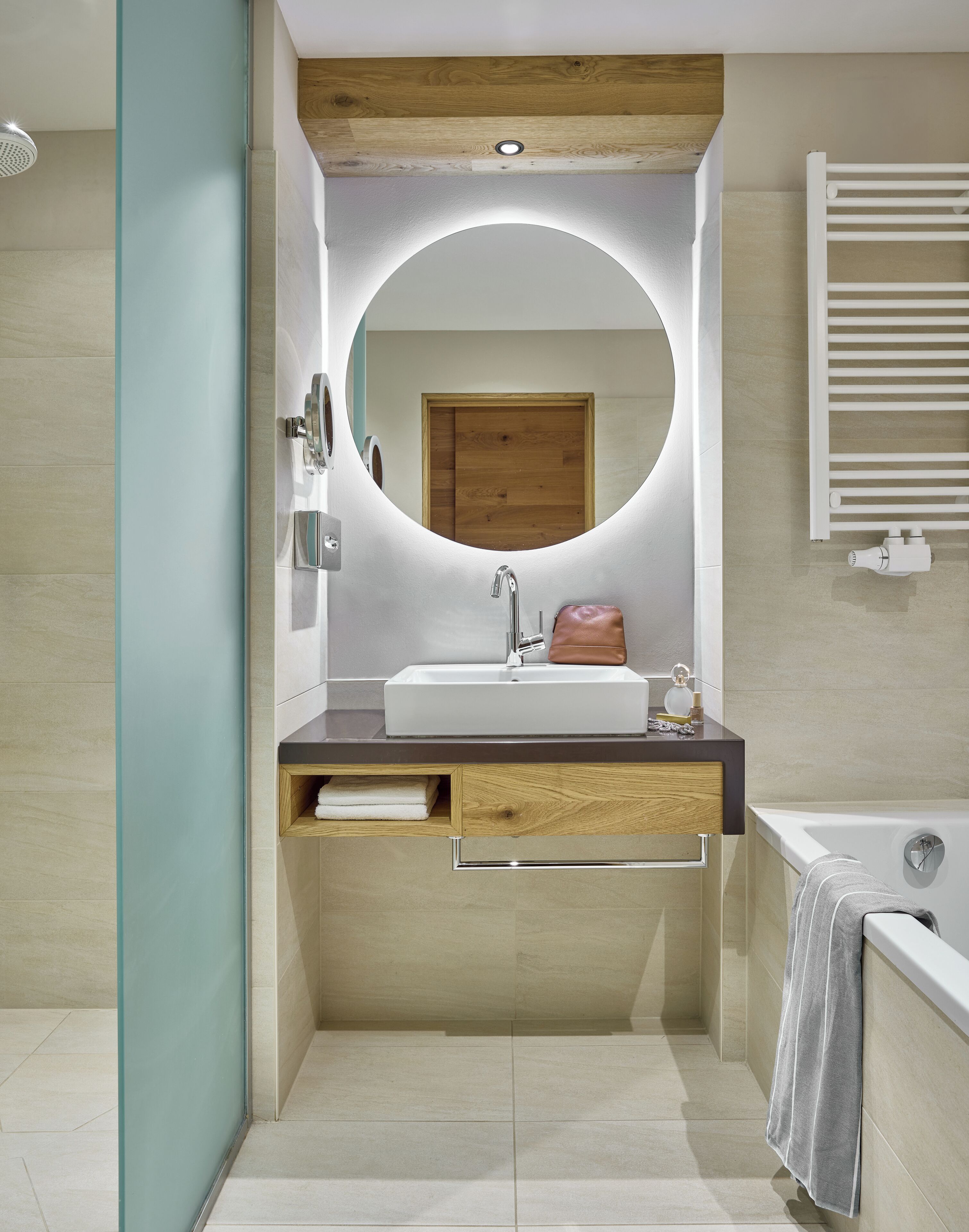 Une salle de bain moderne avec un grand miroir, un lavabo, un porte-serviettes et une baignoire.