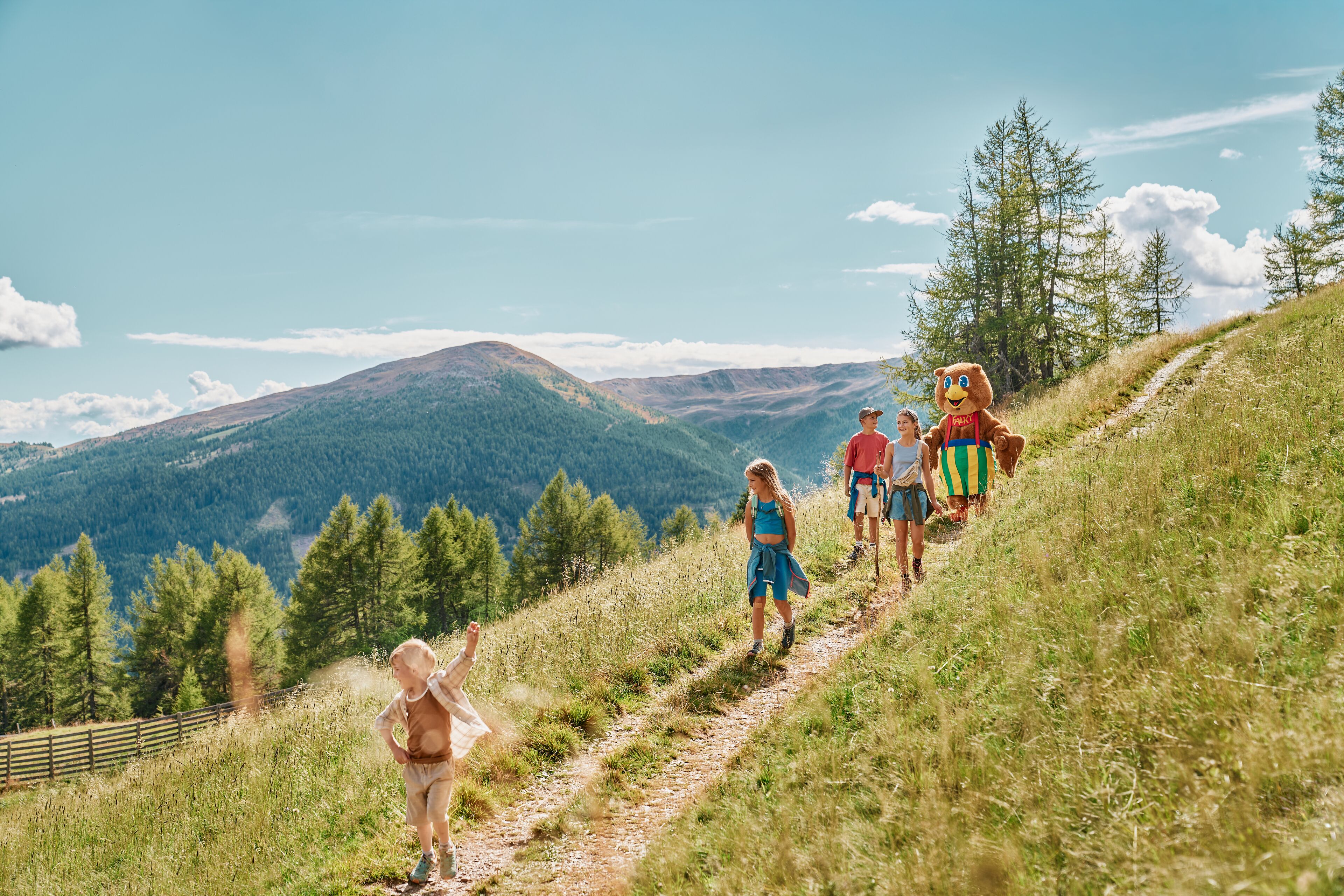 Een groep mensen wandelt over een begroeiing met op de achtergrond een bergachtig landschap.