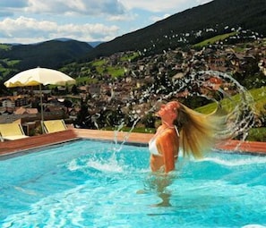 Una persona en una piscina con un paisaje montañoso al fondo.