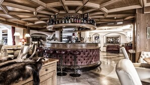 Angolo bar con soffitto in legno, bancone circolare e sgabelli in pelle.