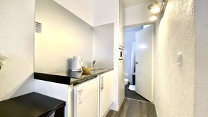A narrow hallway with a kitchenette area featuring a sink, a kettle, and a microwave. - Appart Hôtel Boulogne Résidence (Boulogne-Billancourt)