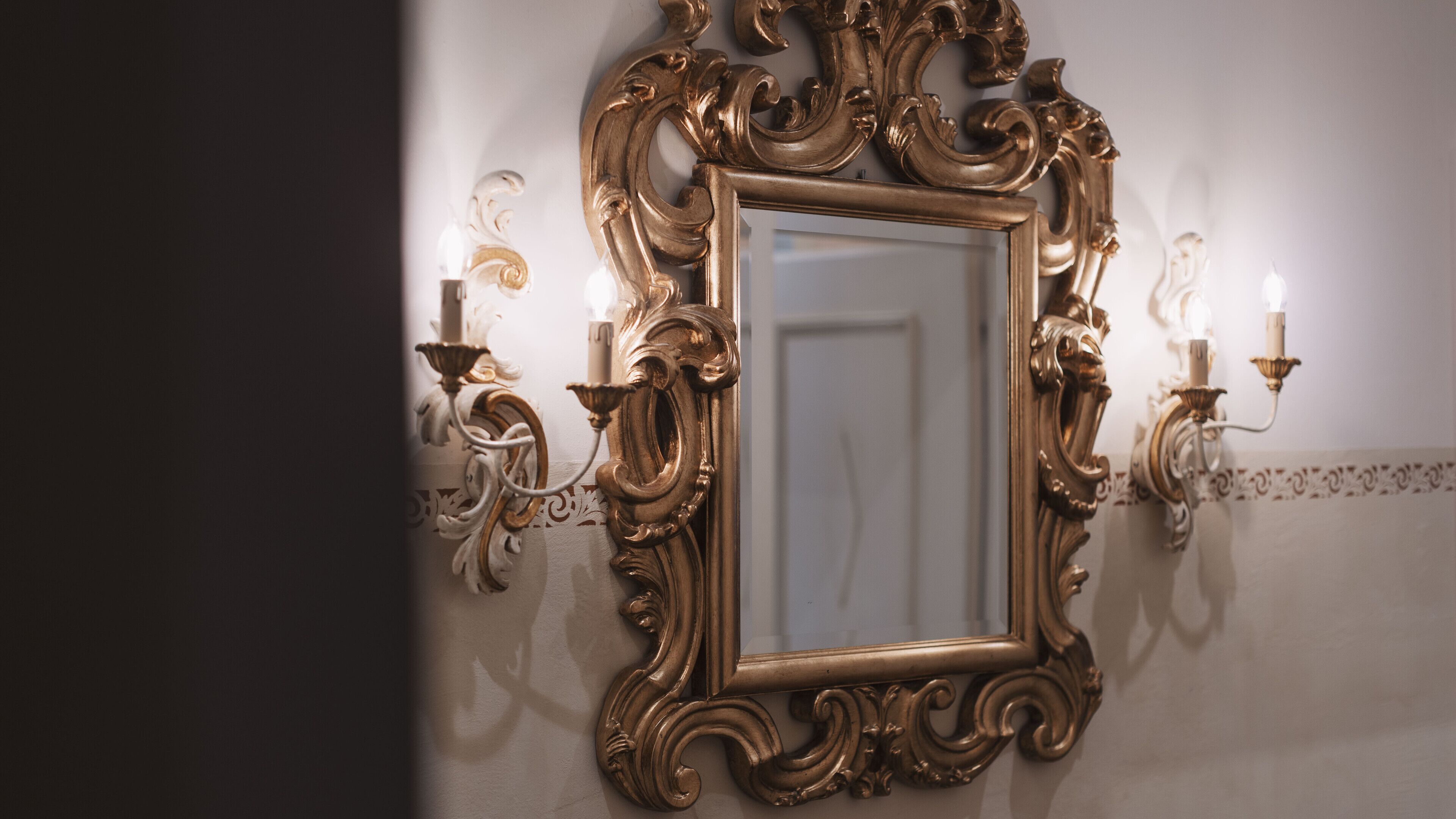 An ornate mirror with a gold frame and candle sconces on either side.