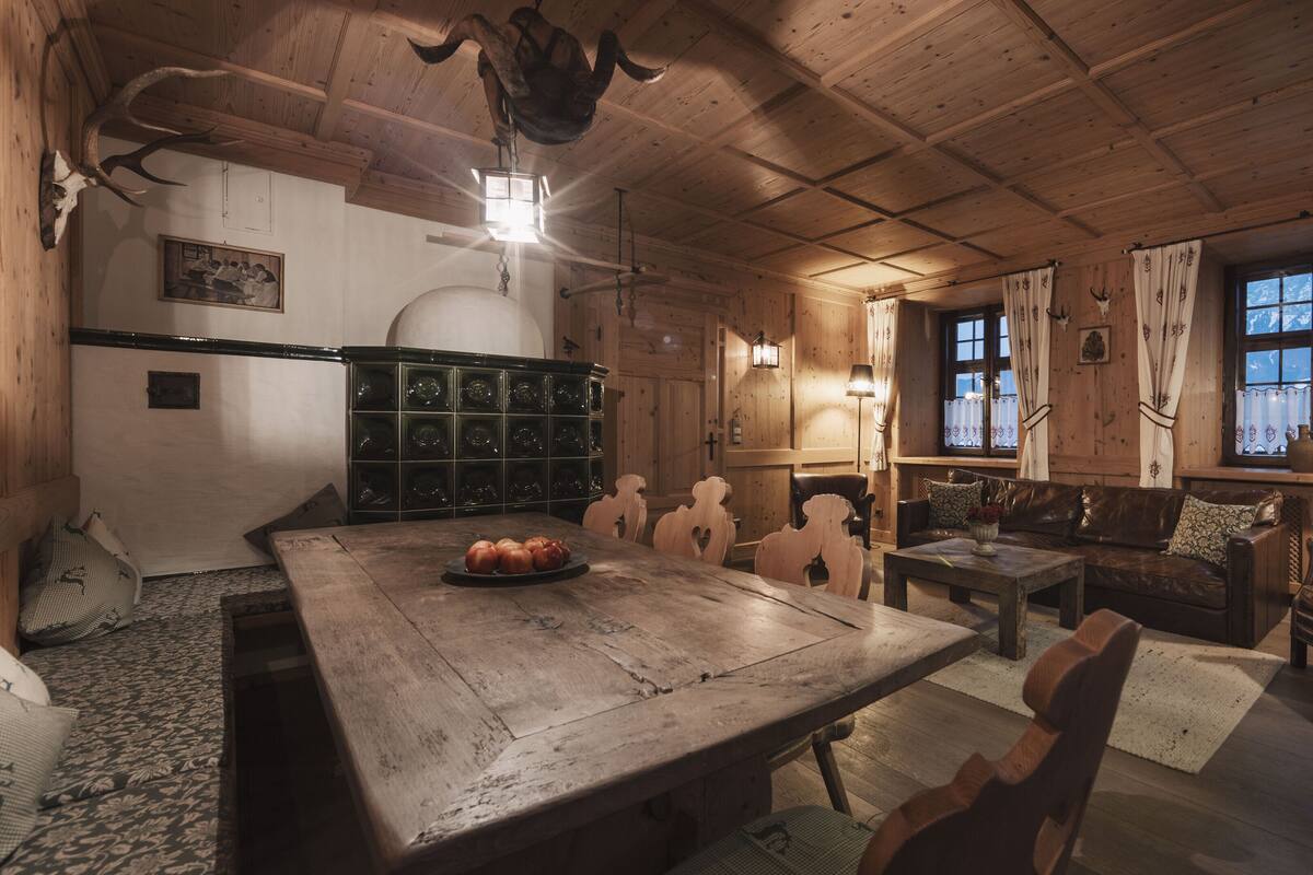 Un interior rústico de madera con una mesa de comedor, sillas, un sofá y una chimenea.