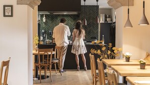 A modern kitchen with a herringbone backsplash, wooden chairs, and a dining area with a table and chairs.