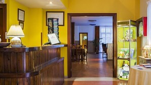 A reception area with a wooden reception desk, a framed certificate, and a small table with brochures. - Arcea Hotel Mirador de Cabrales (Cabrales)