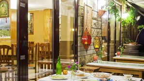 An indoor dining area with tables set for meals, a stone wall, and hanging decorations. - Arcea Hotel Mirador de Cabrales (Cabrales)