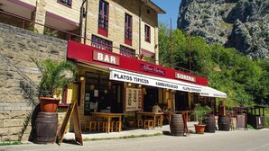 A bar with outdoor seating, a stone facade, and a mountainous backdrop. - Arcea Hotel Mirador de Cabrales (Cabrales)