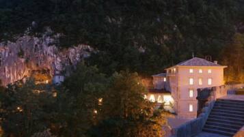 Un edificio con múltiples ventanas, rodeado de árboles y un paisaje rocoso.