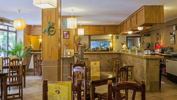 Ein Restaurant mit Holztischen, einer Bar und Blick auf die Straße.