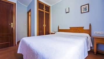 Un dormitorio con cama de madera, mesita de noche, armario e iluminación empotrada en la pared.