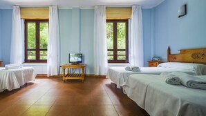 A hotel room with two beds, a television on a wooden table, and large windows with curtains. - Arcea Hotel Mirador de Cabrales (Cabrales)