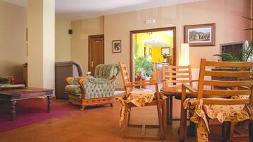 Un salon avec un canapé, des fauteuils, une table basse et un téléviseur.