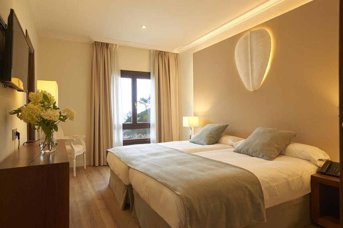Une chambre d’hôtel avec un lit, une table de chevet, une lampe et une vue sur l’extérieur.