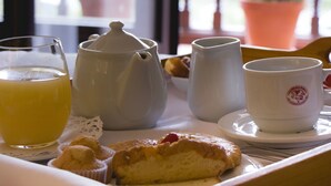 Un plateau contenant des éléments pour le petit-déjeuner, notamment des muffins, une théière, une tasse et un verre de jus d’orange.