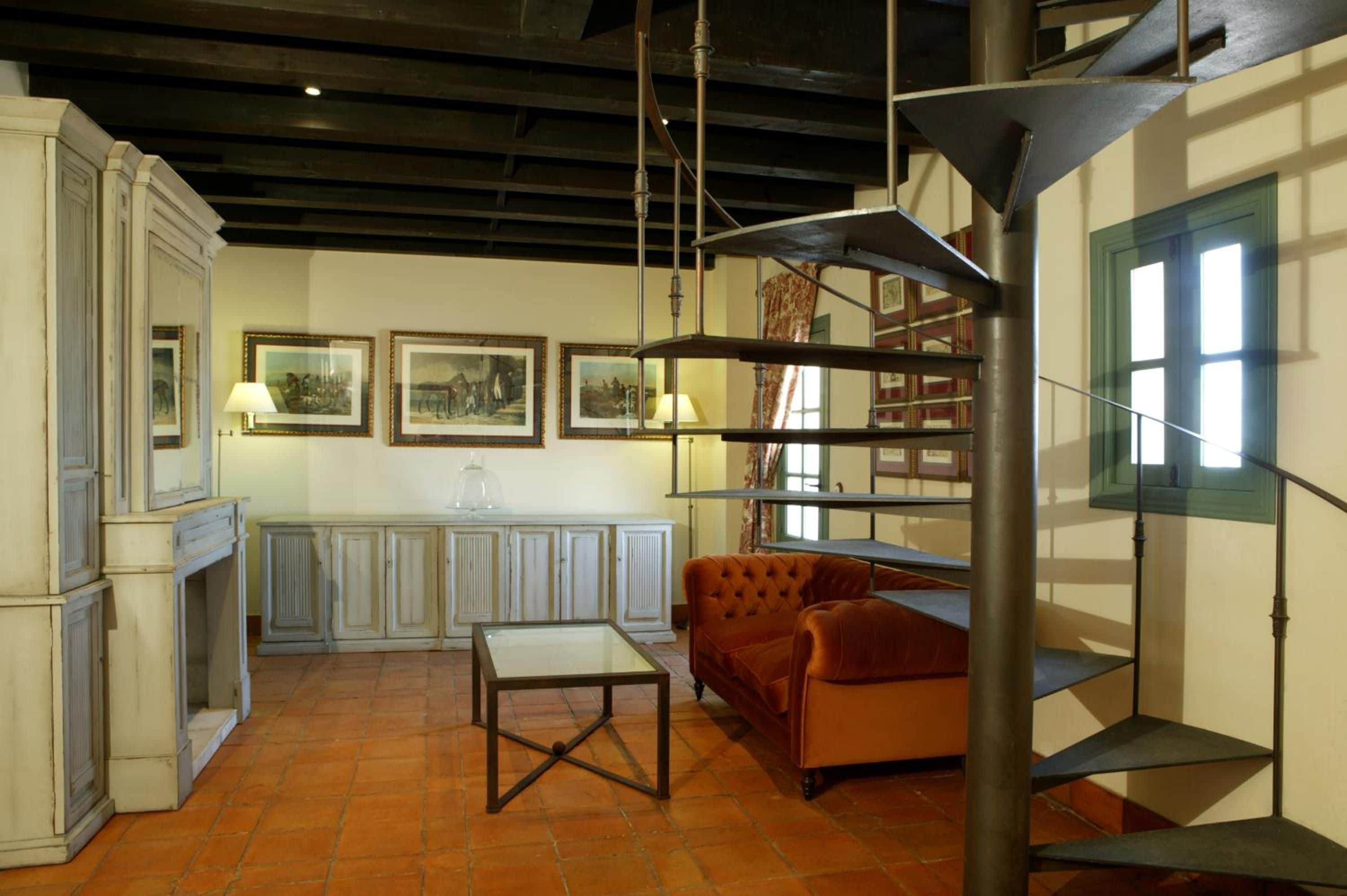 Una habitación con chimenea, un sofá, una mesa y una escalera de caracol.