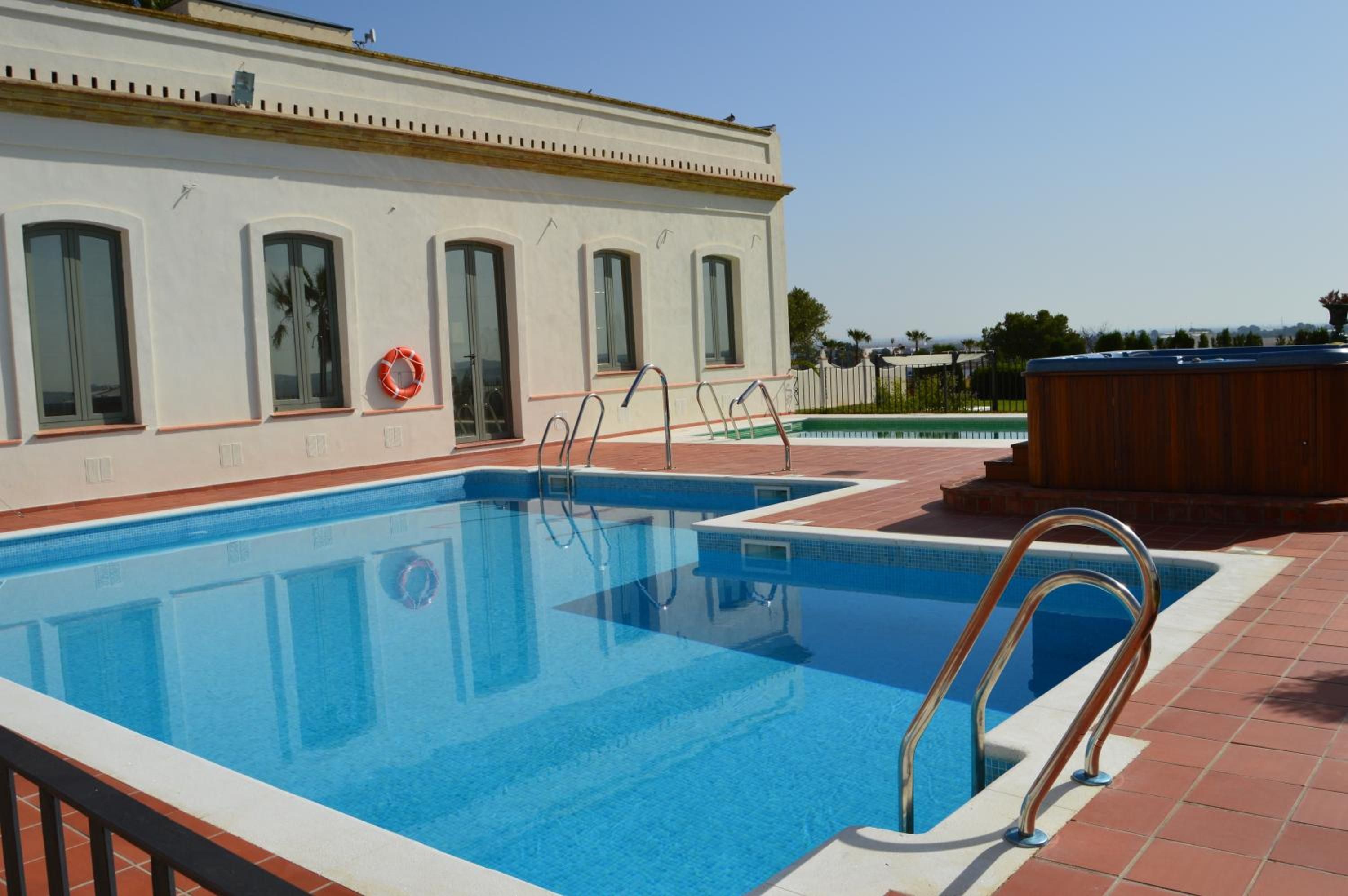 Een zwembad met betegeld zonnedek, een reddingsboei en een jacuzzi.