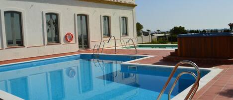 A swimming pool with a tiled deck, a lifebuoy, and a hot tub.