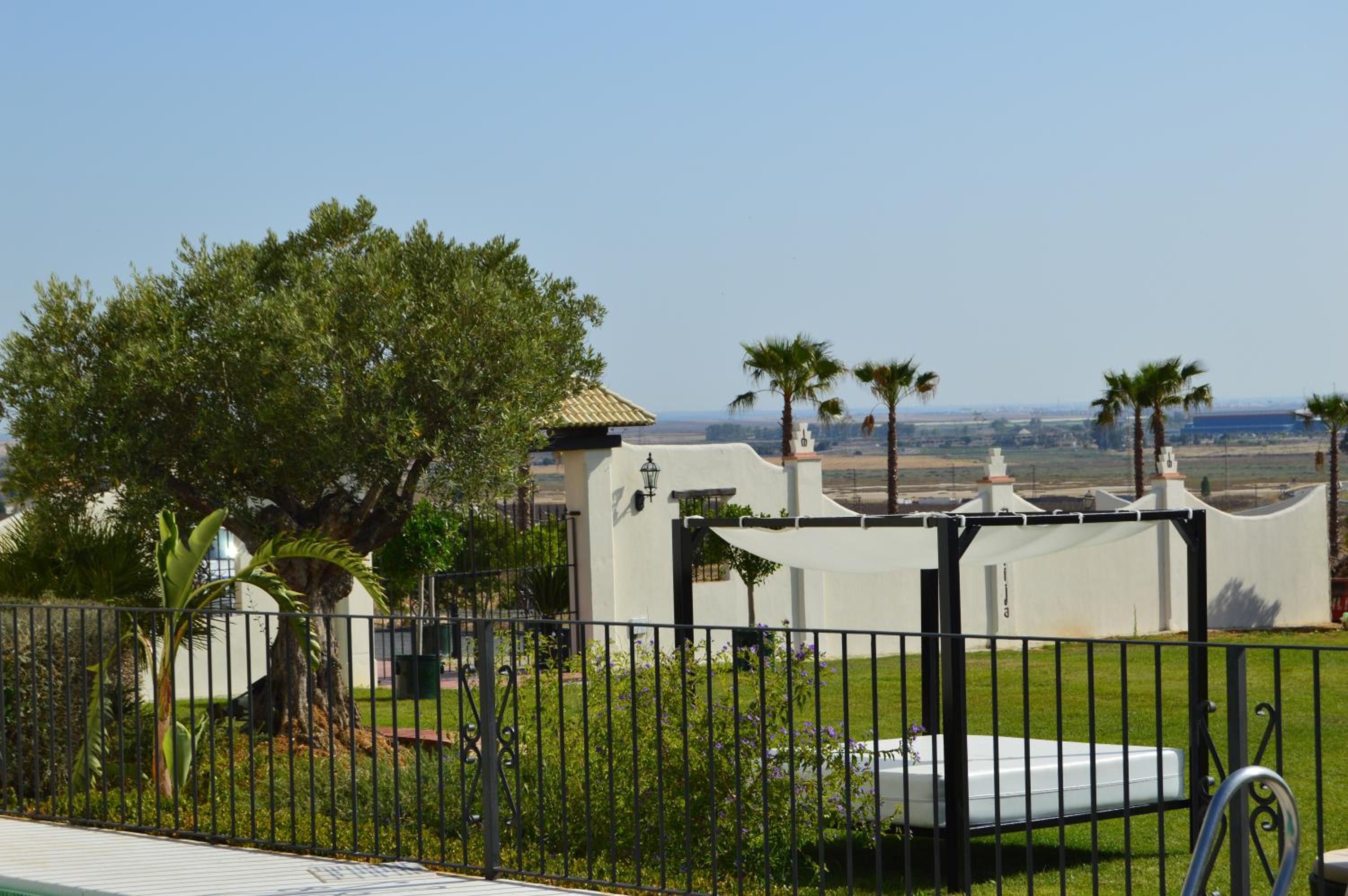 A fenced property with a white building, a pool, and a view of the landscape.
