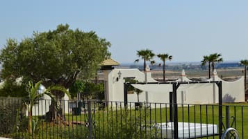 A fenced property with a white building, a pool, and a view of the landscape.