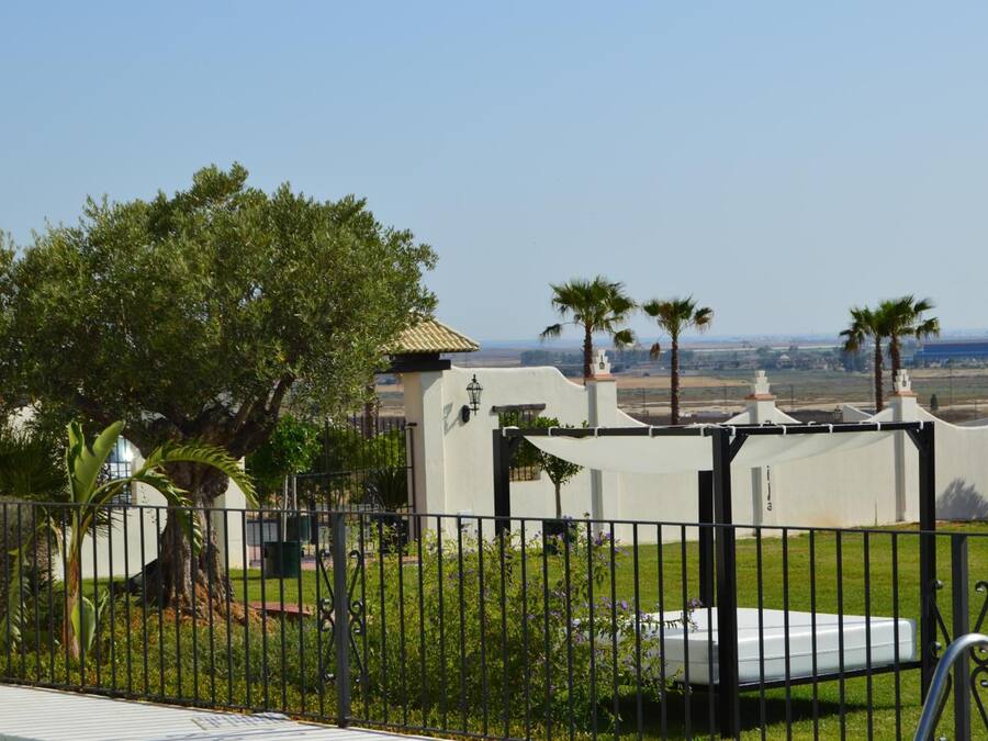 Propiedad cercada con un edificio blanco, una piscina y vistas del paisaje.