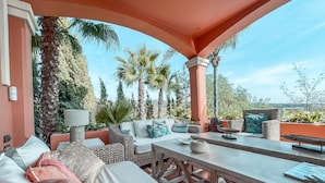 An outdoor seating area with a sofa, table, and chairs, surrounded by palm trees and a clear view of the landscape. - The Marbella Heights Boutique Hotel (Marbella)