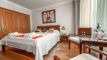 Una habitación de hotel con una cama grande, un armario de madera, un escritorio con silla y un cuadro en la pared.