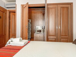 Et hotelværelse med seng, garderobe og minibar.