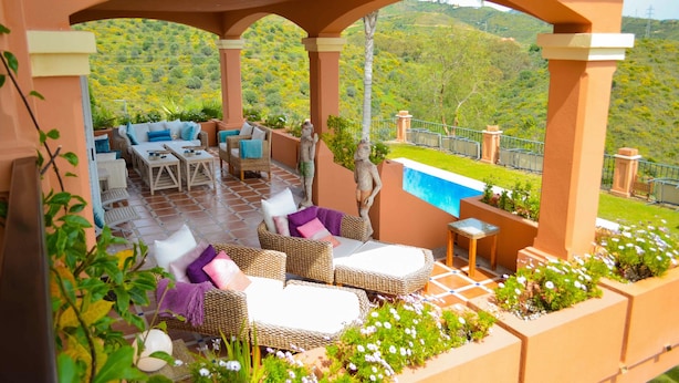 An outdoor patio with wicker furniture, a pool, and a view of a green hillside. - The Marbella Heights Boutique Hotel (Marbella)