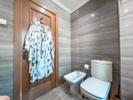 Ein Badezimmer mit Holztür, einem Bidet und einer Toilette.