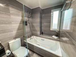 Un baño moderno con bañera, inodoro y cabina de ducha de vidrio.