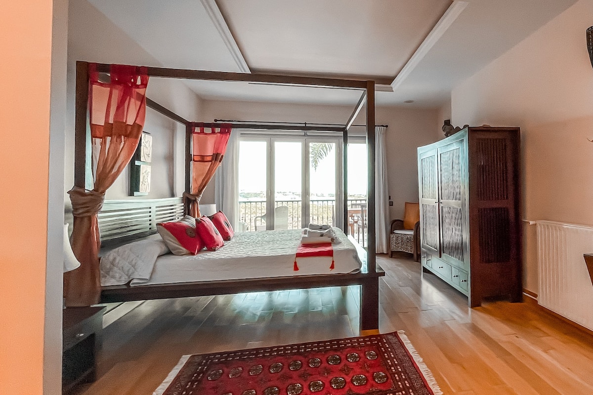 Een slaapkamer met een bed, een kledingkast, een raam met gordijnen en uitzicht op buiten.