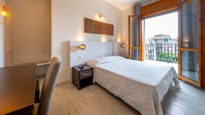 Ein Hotelzimmer mit Bett, Nachttisch, Stuhl und einem großen Fenster mit Aussicht.