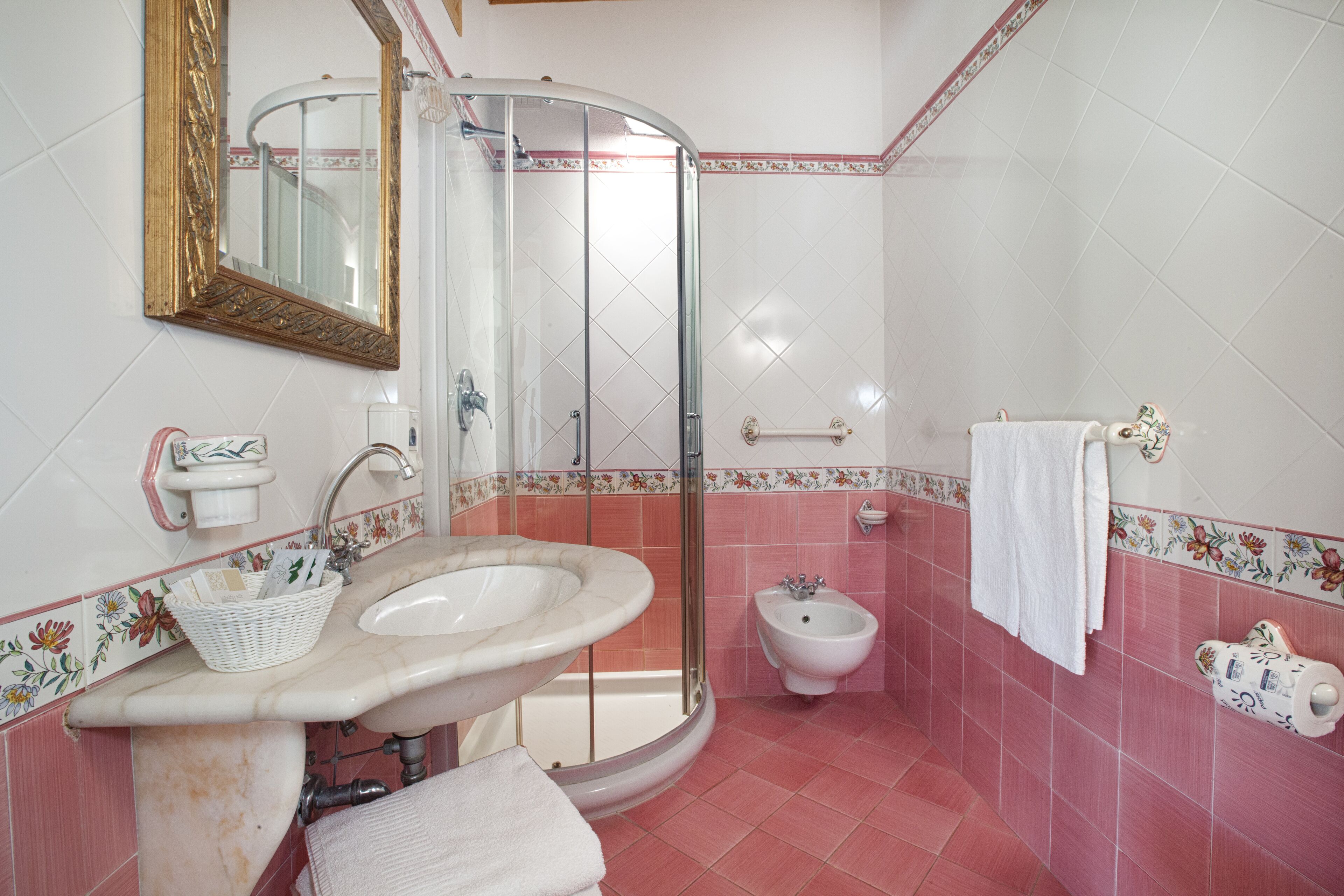 A bathroom with a sink, mirror, shower, and bidet.