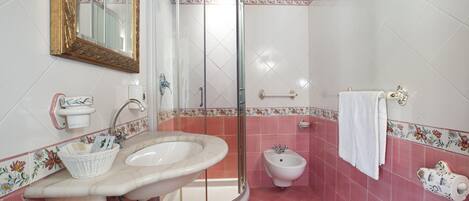 A bathroom with a sink, mirror, shower, and bidet.