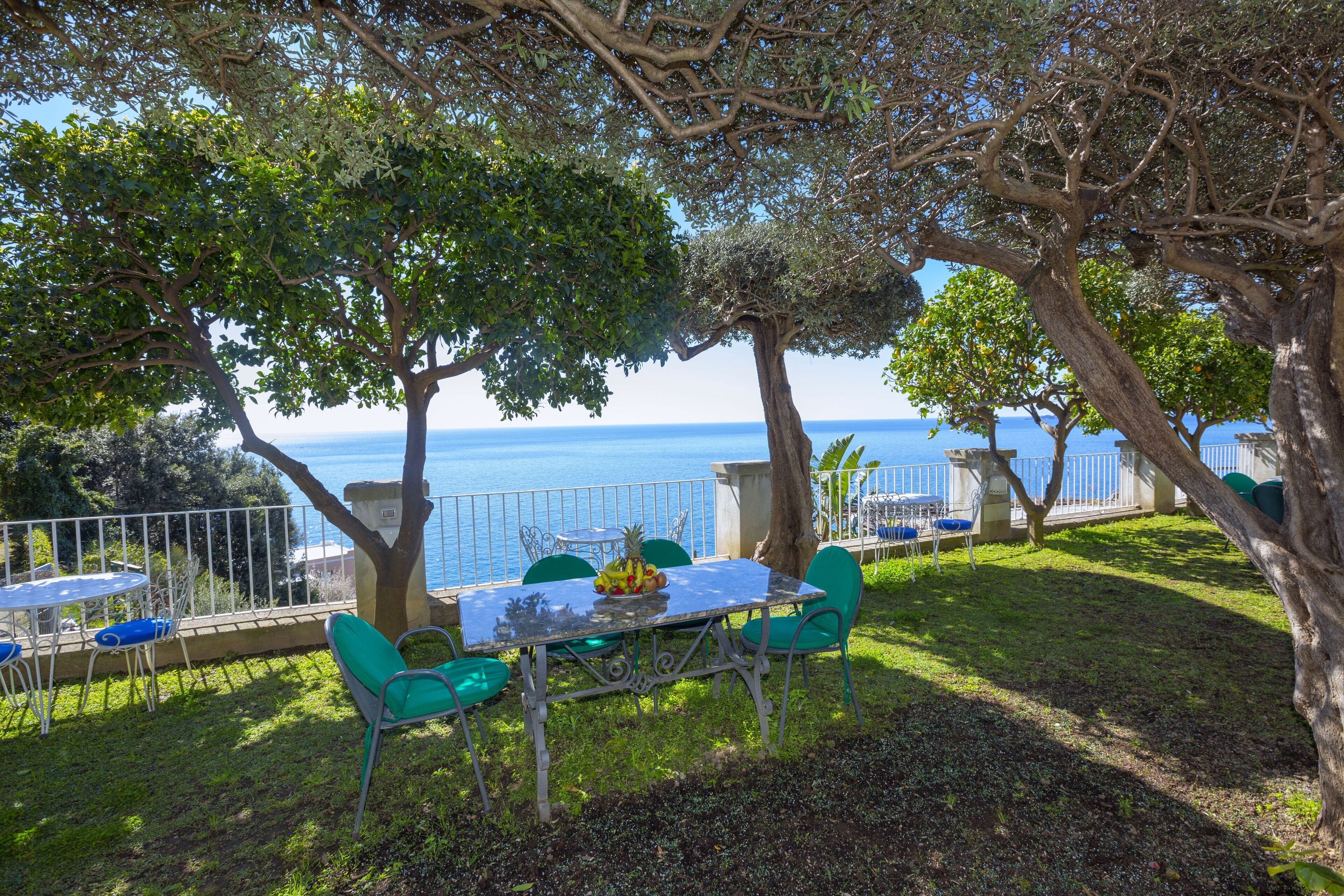 Un espace extérieur aménagé pour prendre les repas, avec une table et des chaises, donnant sur une étendue d’eau.