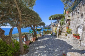 A stone pathway leading to a coastal area with potted plants and a view of the sea. - La Maliosa D'Arienzo (Positano)