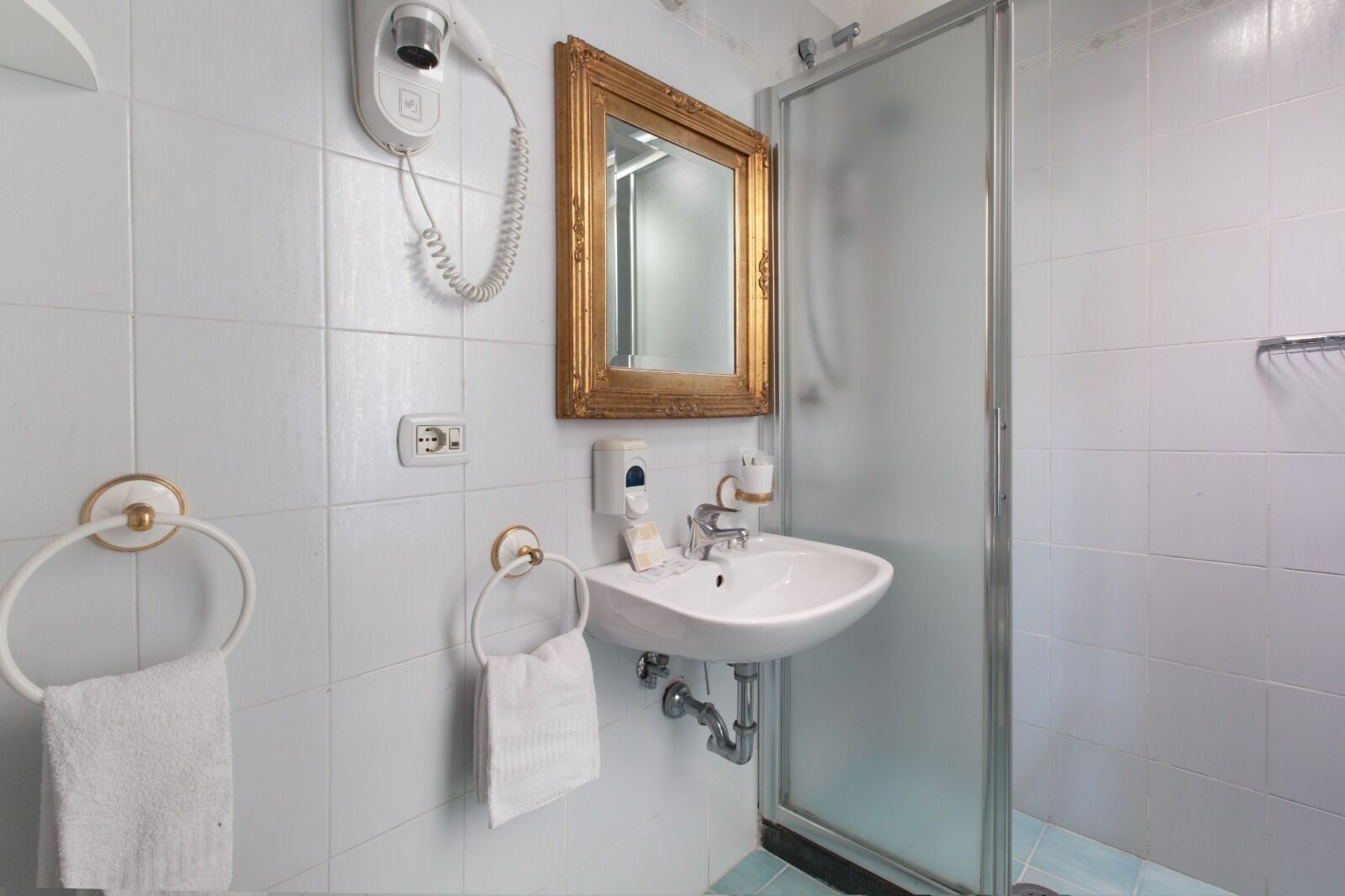 A bathroom with a white sink, a mirror, a hairdryer, and a towel rack.