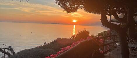 A sunset over a calm body of water with a view of distant land.