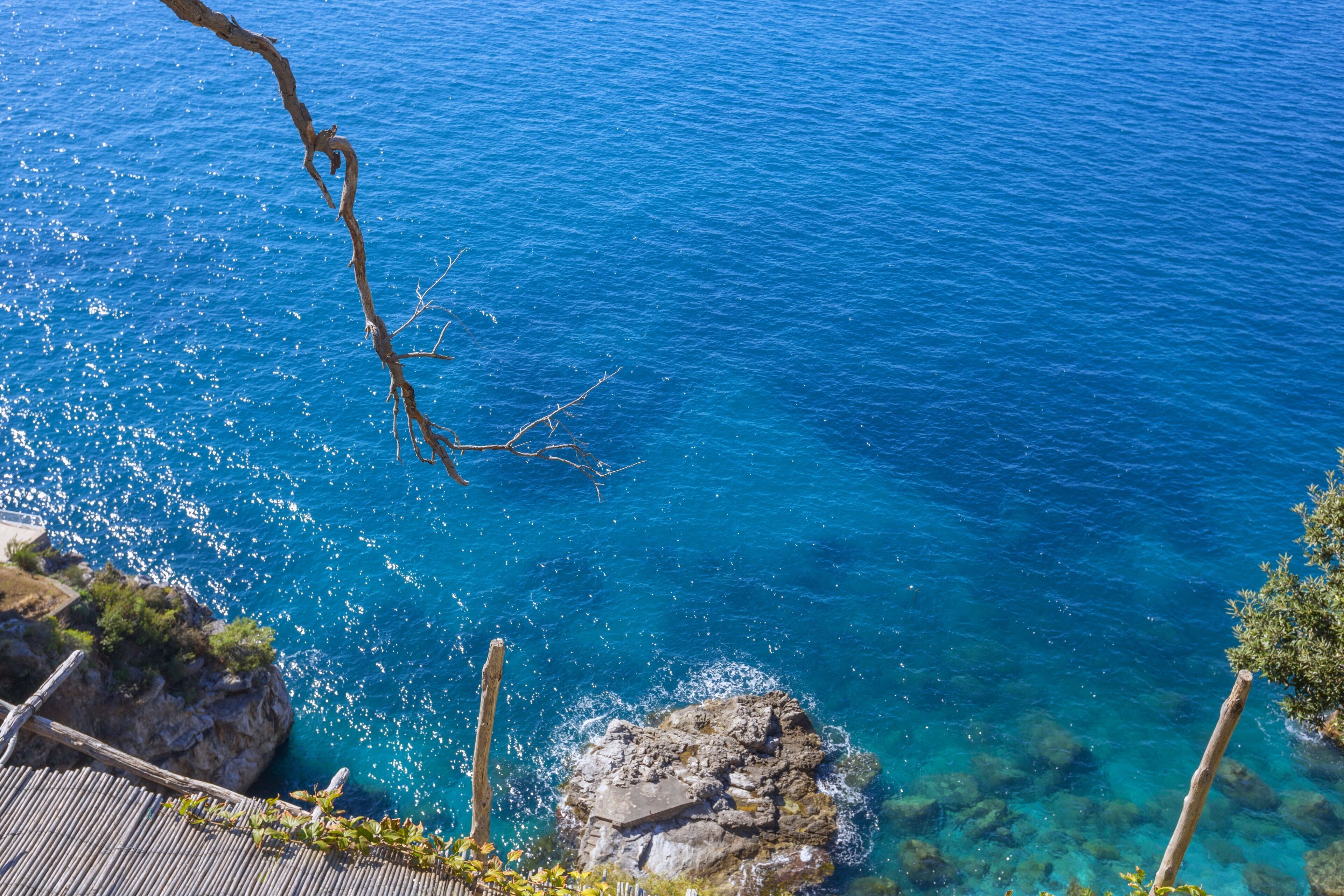 Une vue sur la côte, avec une eau d’un bleu limpide, un paysage rocheux et une structure en bois.