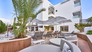 A hotel with outdoor seating, including lounge chairs and umbrellas, and a pool area. - Flacalco Hotel & Apartments (Capdepera)