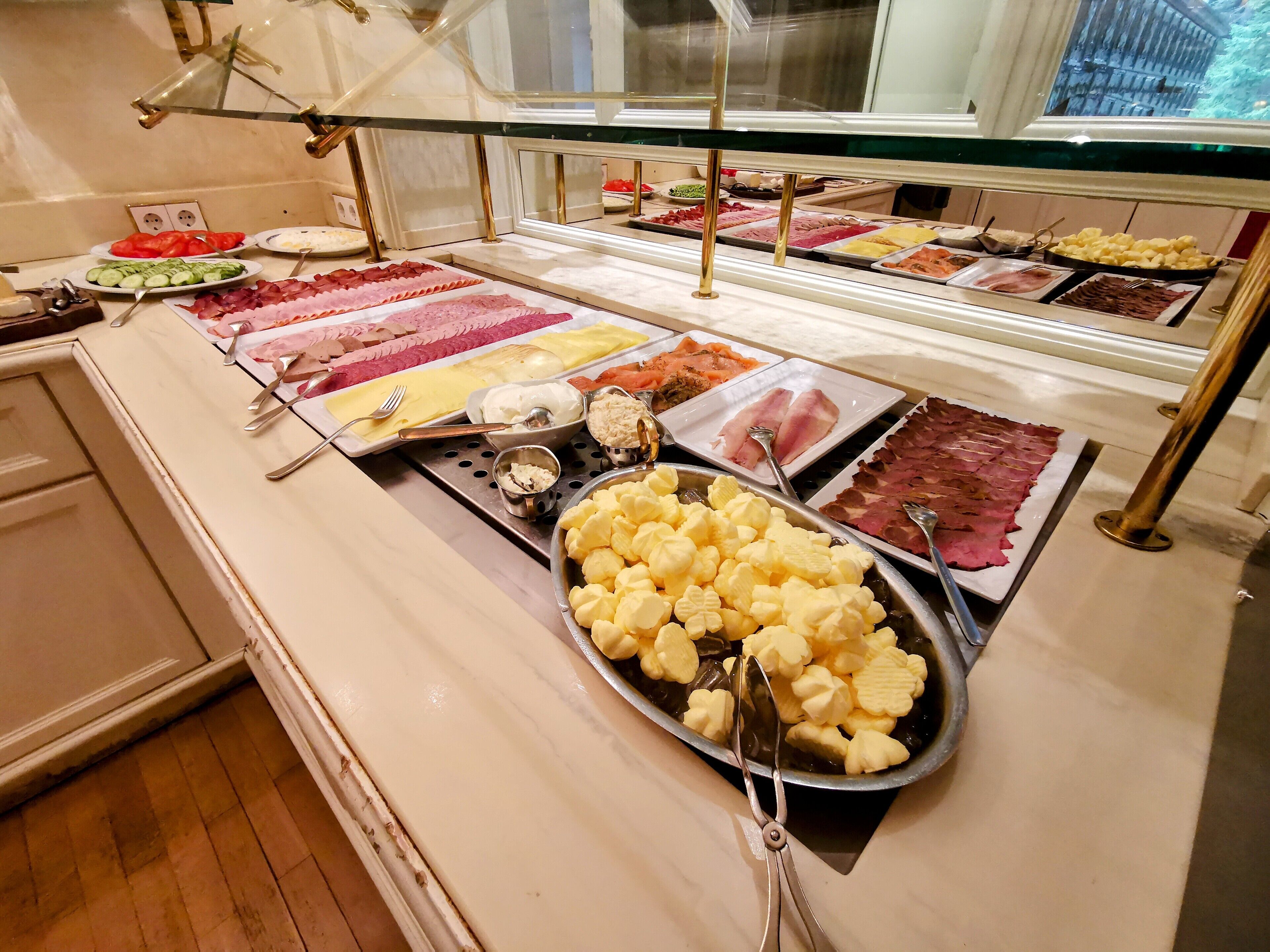 A buffet with various food items including meats, cheeses, and vegetables.