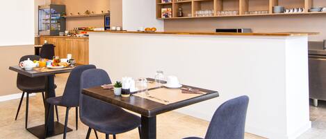 A modern dining area with a central island, seating, and a kitchen in the background.